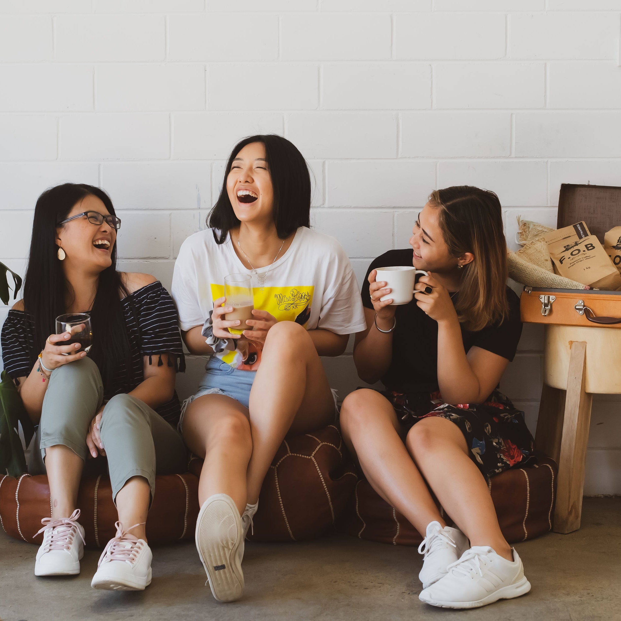 three girls laughing all holding their coffee cups